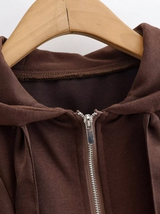 Detailed close-up of brown hoodie with smooth fabric texture and silver metal zipper