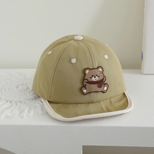 Detail of baby soft brim cap featuring brown bear embroidery patch and khaki cotton fabric