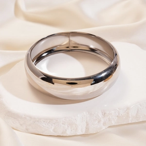 Macro detail of silver minimalist metal bangle on white stone with silk fabric