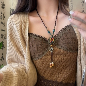 Ethnic beaded pendant necklace with vintage metal disk and leaf tassels on a long rope