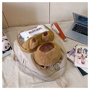 Detail of beige nylon backpack with plush Capybara and Chewy Vuitton bone accessory