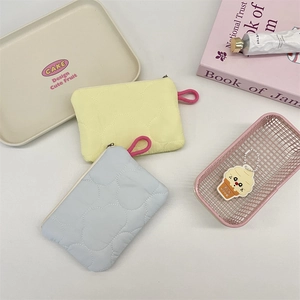 Close-up of quilted heart pattern pouches in pastel yellow and blue with metal zippers
