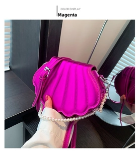 Detail der rosaroten Muschel-Tasche mit Wellentextur und elegantem Perlen-Tragegriff