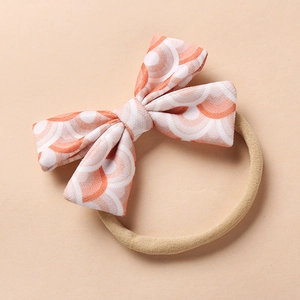 Detail of baby headband featuring a bow with coral and white wave patterns