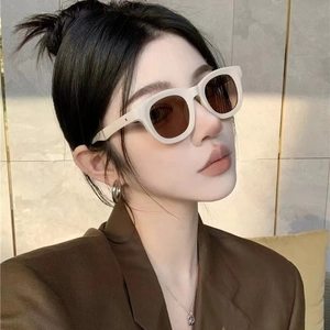 Chique beige zonnebril met dik montuur en bruine glazen gedragen door een mooi model