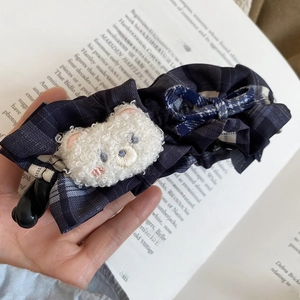 Détail d'une pince à cheveux en tissu écossais bleu marine avec un ours en peluche blanc