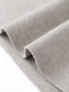 Macro shot of light gray knit fabric showing the waffle texture and fine wool detail
