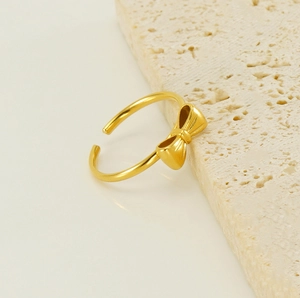 Close-up of golden bow-shaped open ring on a textured natural stone surface