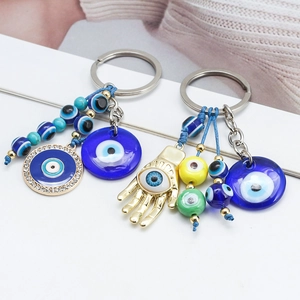Detail of Hamsa Hand and Evil Eye keychains with vibrant blue beads and gold accents