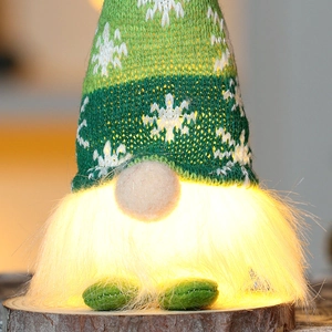 Close-up of a green knitted Christmas gnome with a snowflake pattern and warm LED lights