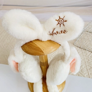 Detail of white plush ear muffs with cute Love embroidery and sun icon on soft fur