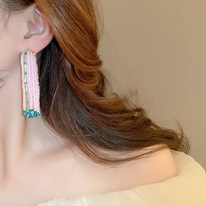 Detail of pink handmade beaded fringe earrings on a model in a bohemian resort style
