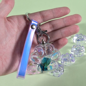 Detail of transparent cat paw keychain with blue liquid filling and laser lanyard