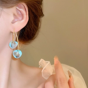 Detail shot of light blue translucent resin drop earrings with gold double arc hangers
