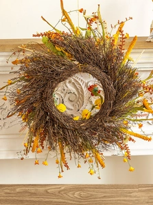 Détail de la couronne d'automne avec fleurs orange sur une cheminée blanche chic