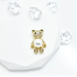 Golden bear pendant accessory with crystal rhinestones and a white pearl on a white base