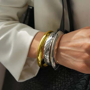 Detail of geometric metal bangles featuring polished gold and hammered silver finishes