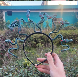 Detailed view of dark green Medusa snake headband with red accents in outdoor setting