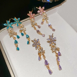 Close-up of three flower tassel earrings in blue, pink, and purple crystal settings