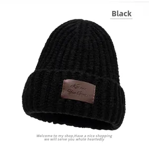Close-up of black ribbed knit hat featuring a dark brown embossed leather logo patch