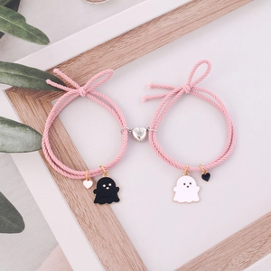 Pink magnetic couples bracelets with cartoon ghost enamel charms on white wood background