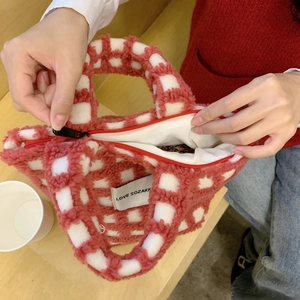 Detail view of pink checkerboard plush bag interior showing zipper and brand label