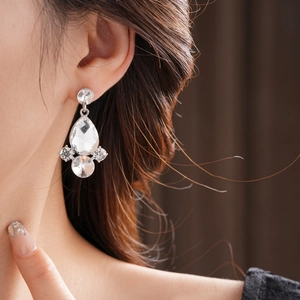 Dettaglio di eleganti orecchini a goccia in argento con strass scintillanti su modella