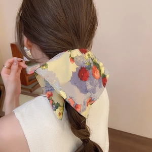 Detailed back view of a large floral bow hair clip styled on a brown braided ponytail