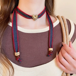Detail of bohemian heart pendant necklace with red and blue woven strap and wood beads