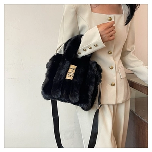 Detail view of black faux fur tote bag with Have a Nice Day label worn by model