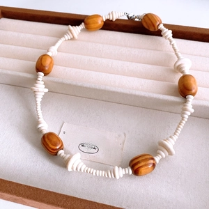 Detail of vintage beaded necklace with brown wood beads and white stone pendants on a box