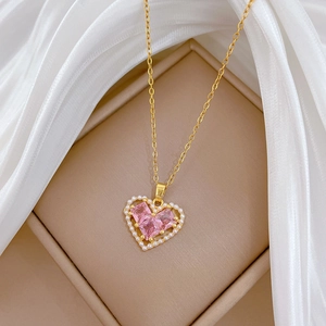 Detail showing the pink crystal and pearl heart pendant on a gold titanium steel necklace