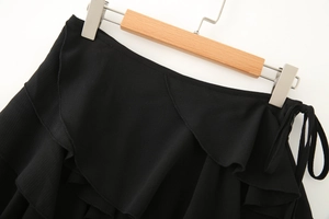 Vue détaillée de la jupe à volants noirs avec tissu crêpe texturé et nœud de serrage latéral