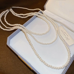 Vista dettagliata della collana di perle bianche a più strati in una confezione regalo con carta