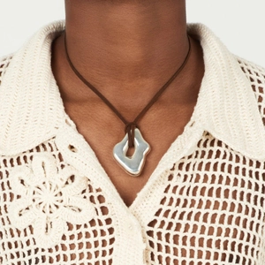 Detail of silver irregular liquid metal pendant on a cord worn by a model