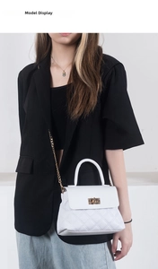 Close-up of white quilted chain bag worn by a model in a black blazer suit