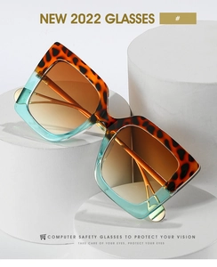 Detail view of large square leopard print sunglasses on a geometric white pedestal