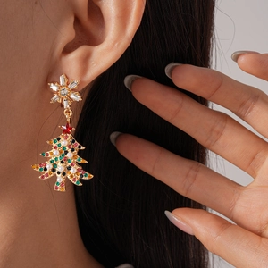 Close-up of golden Christmas tree earring with colorful rhinestones and white pearls