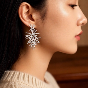Detail of silver long drop earrings with white zircon crystals on a female model