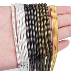 Copper plated snake bone chains in gold silver and black colors held in hand