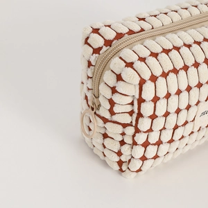 Macro detail of plush checkered makeup bag featuring soft texture and metal ring zipper