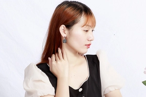Elegantly designed round drop earrings with black tree pattern on female model