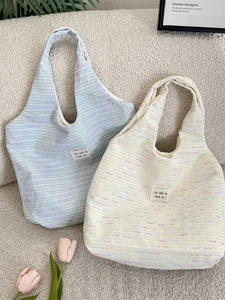 Knitted tweed tote bags in light blue and cream with colorful stitching and brand label