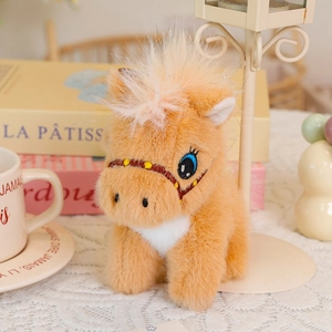Detailed view of a plush pony keychain with blue eyes on a French-style cafe table