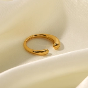 Detail of a minimalist gold open ring with smooth finish on a beige silk background