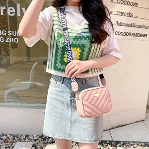 Detail of pink quilted crossbody bag with stylish wide jacquard strap in street setting
