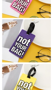 Close-up of flexible PVC luggage tags in pink, purple, and yellow with embossed text