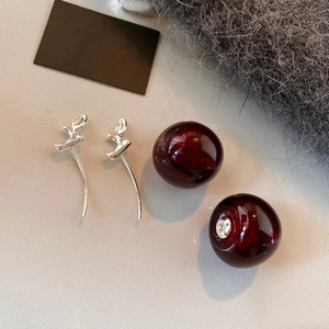 Close-up of resin cherry pendant earrings with silver vine-shaped metal details