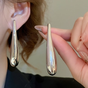 Detail macro of silver-tone teardrop earrings with a high-polished mirror finish