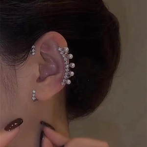 Detail of silver ear cuff with pearls and diamonds worn in layered jewelry style